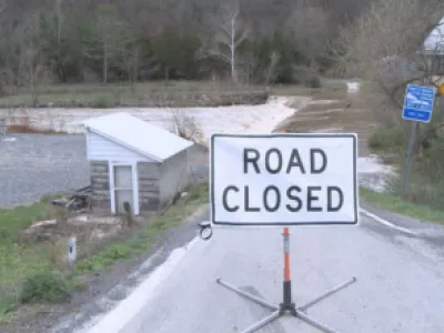 Image of Road Closed sign in front of a road washed out by flooding. 
